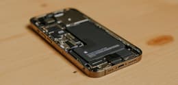 Ein geöffnetes iPhone 13 mini wird angezeigt, man kann die Batterie sehen